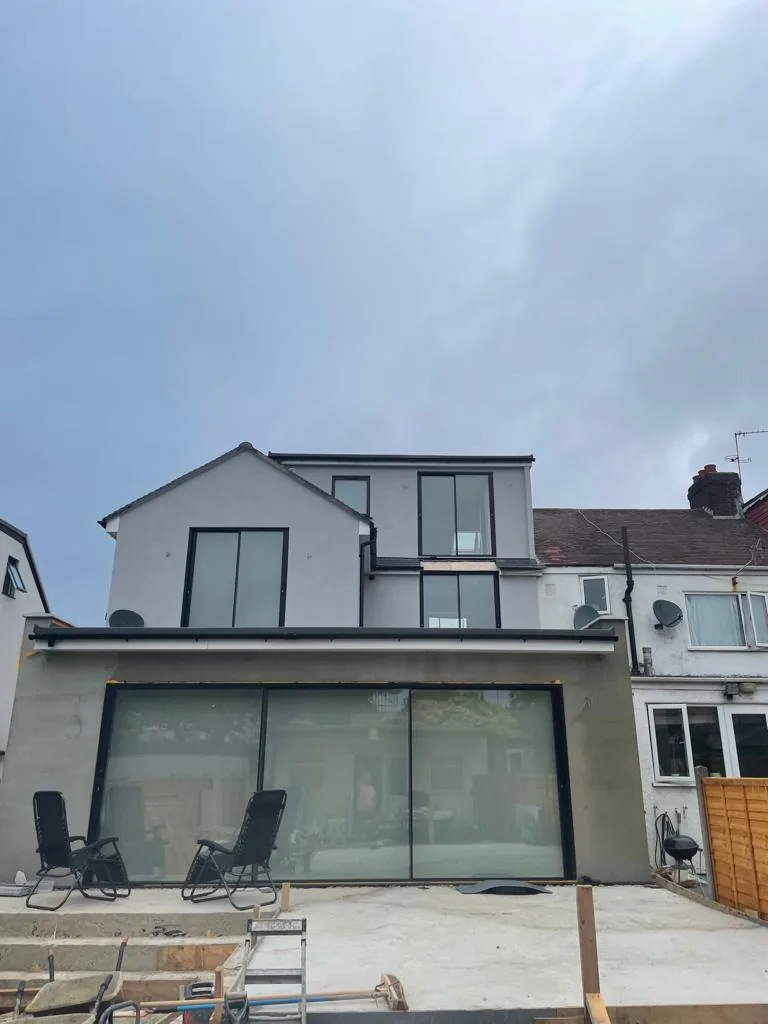 After: a finished rendered extension with full-width glazing and an upper-floor dormer